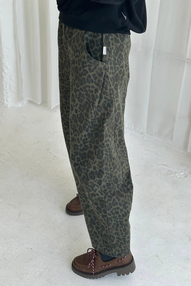 Arc Pants from Le Bon Shoppe. Barrel leg trousers made from durable cotton canvas. Featuring an elastic high waist, deep side pockets, and a slightly curved, cropped leg with a unique side panel. Leopard print on dark green background.