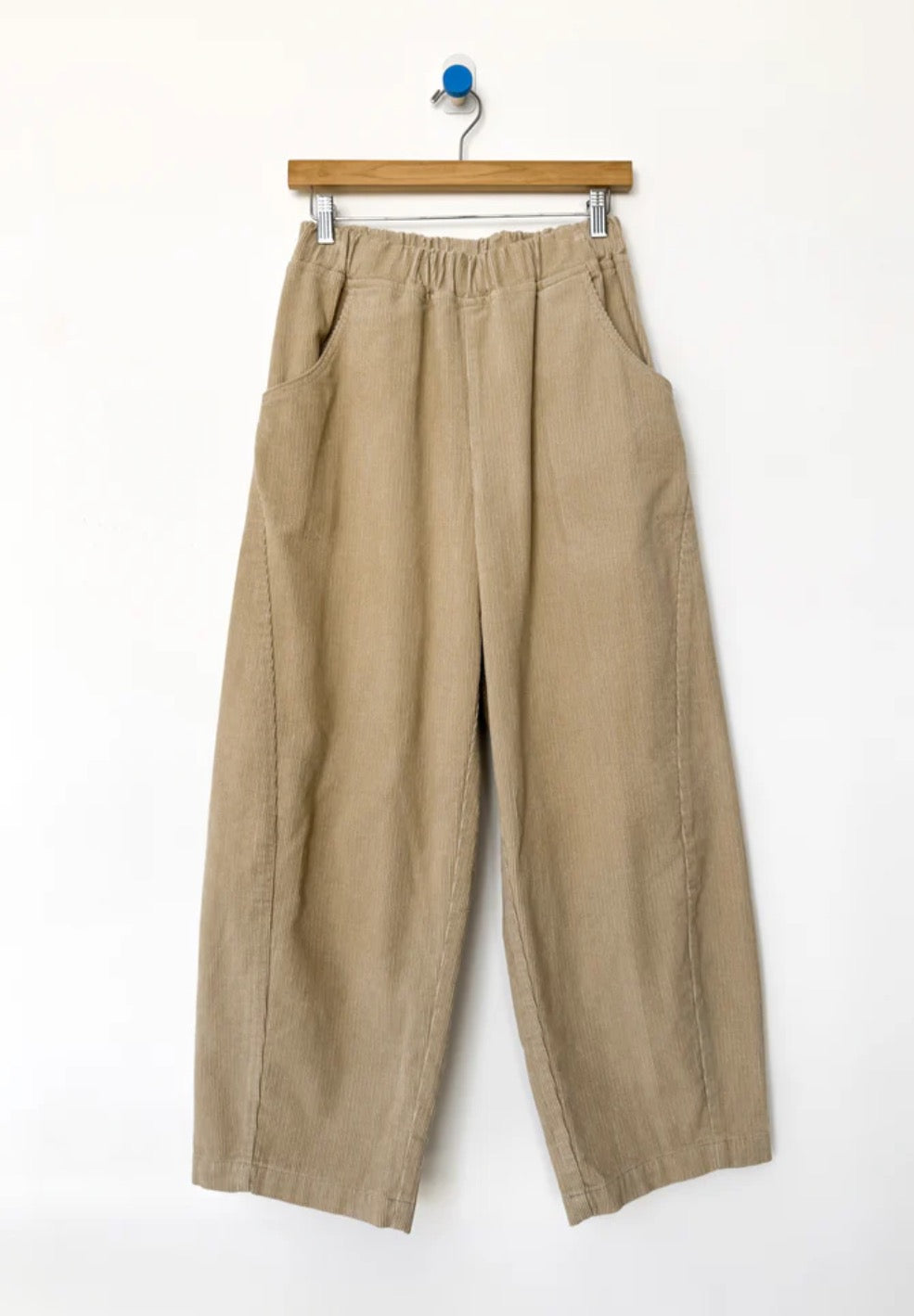 Beige wide-leg corduroy Arc pants from Le bon Shoppe hanging on a wooden hanger against a white background