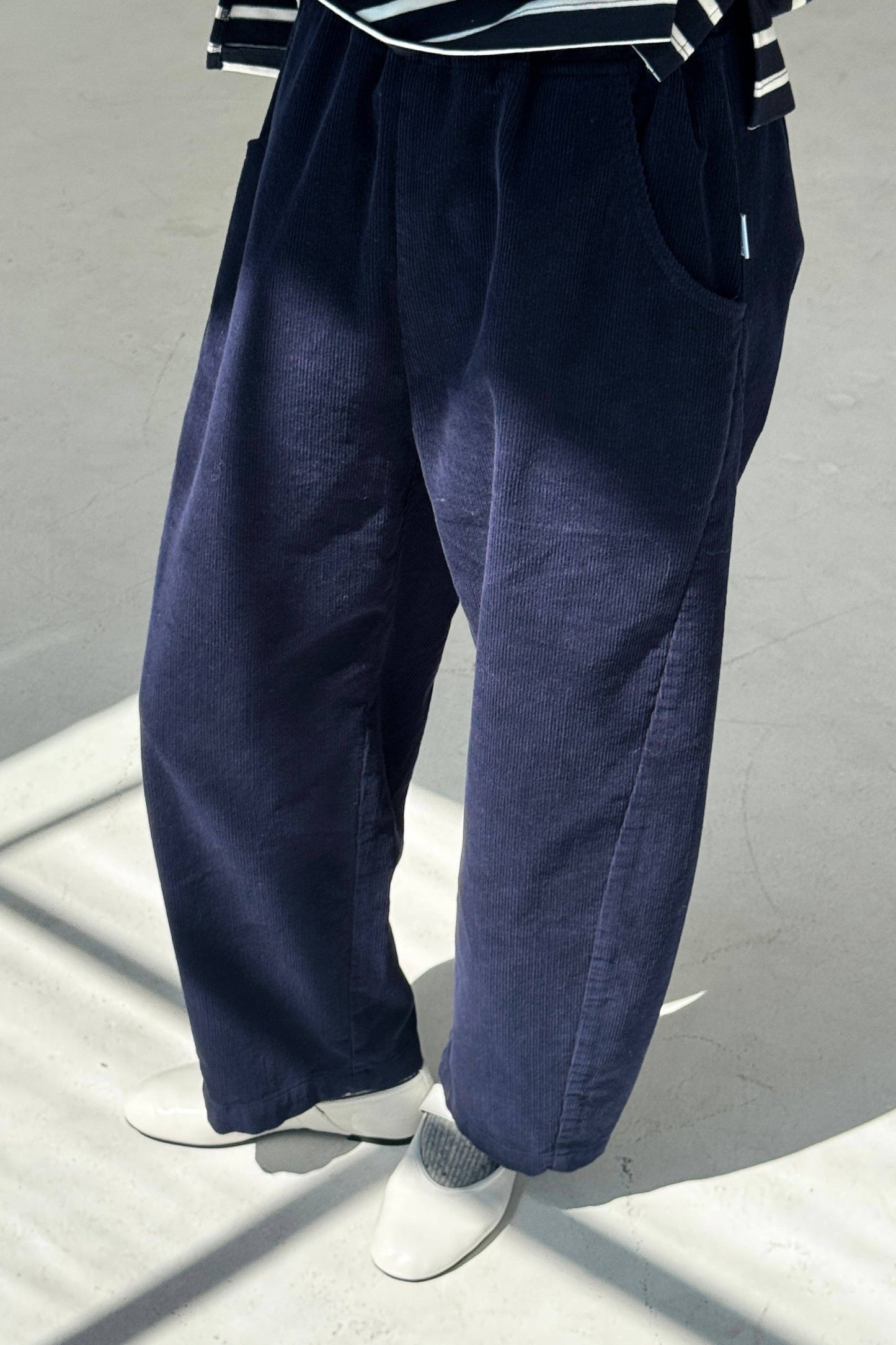 Navy blue corduroy barrel-leg Arc pants worn by a person on a light gray background