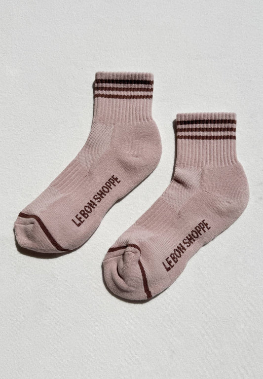 Pair of pink socks with brown stripes and 'Le Bon Shoppe' branding on a light gray background