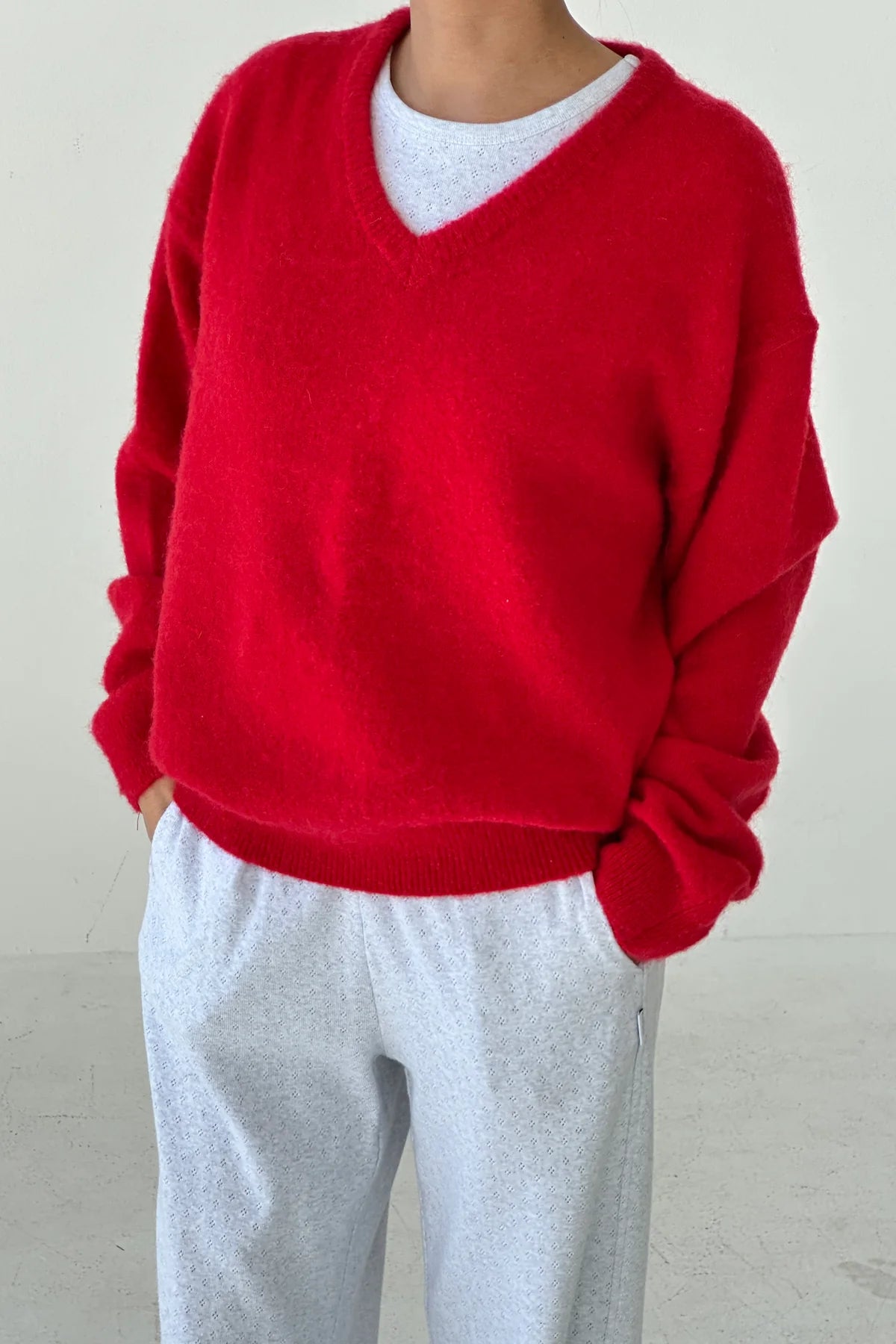 Woman wearing the bright red James mohair jumper from Le Bon Shoppe and gray pants against a plain background