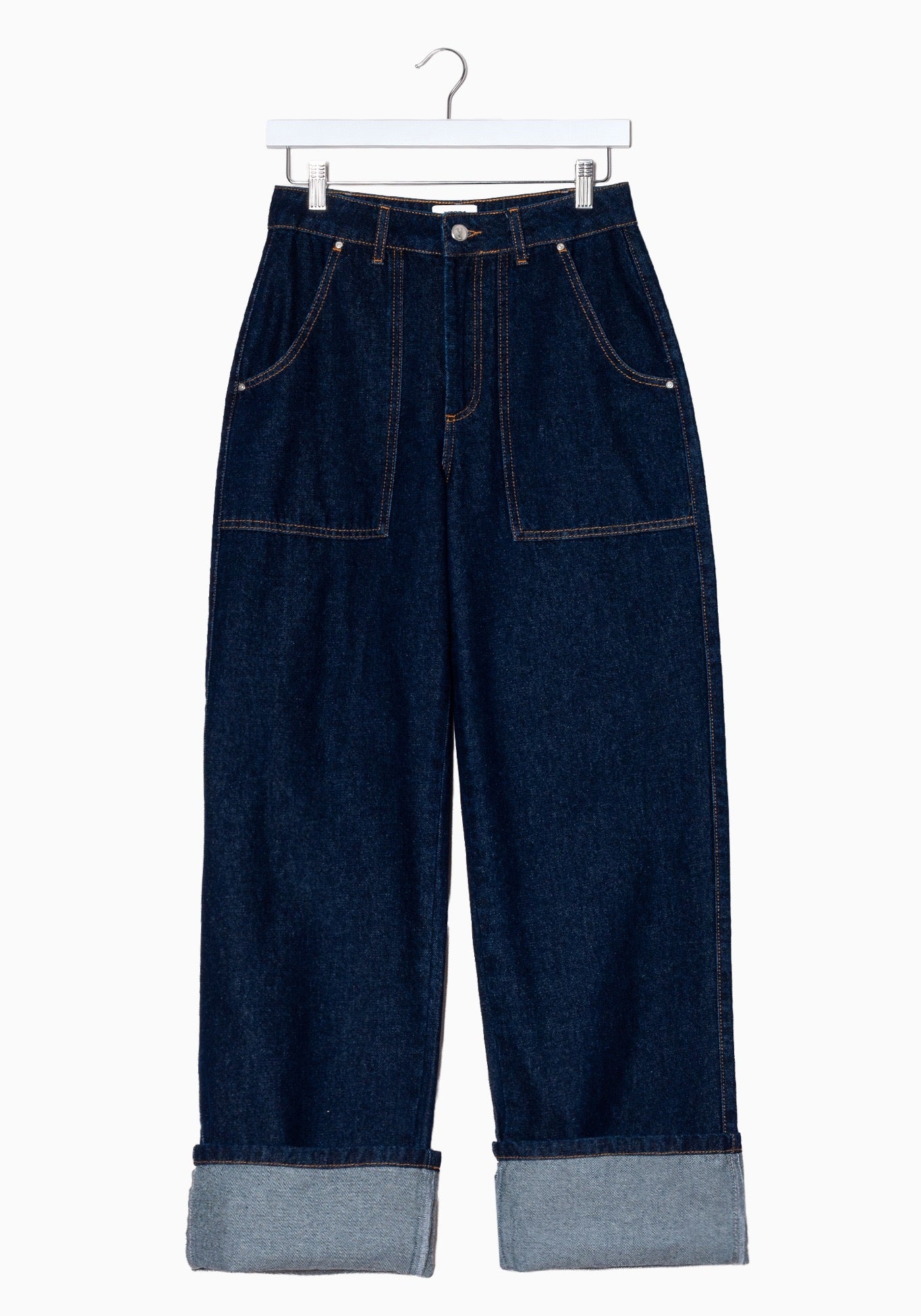 Dark blue denim cropped pants by  Mademoiselle Yeye with a cuffed hem and dual front patch pockets, hanging on a white hanger against a plain white background.