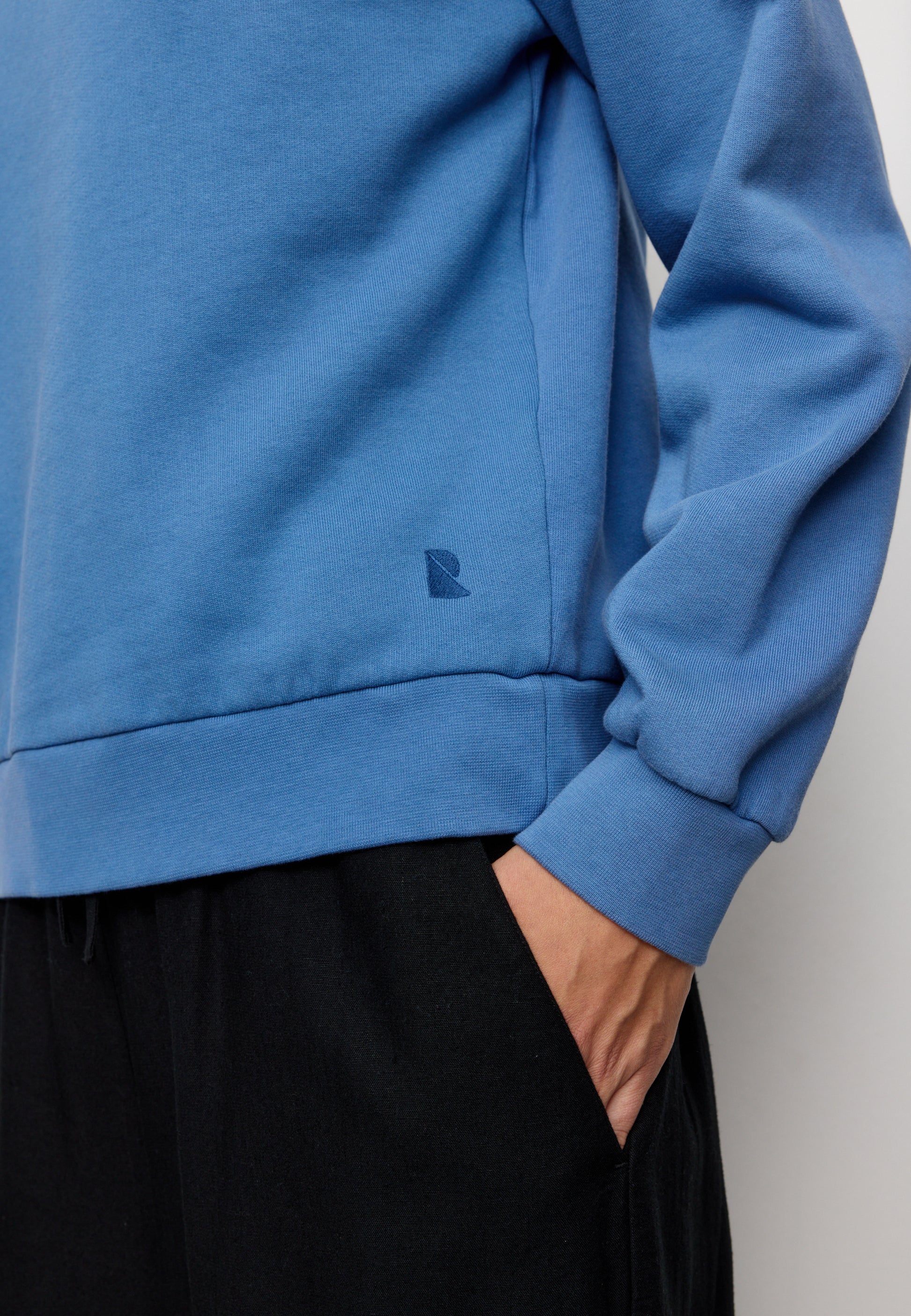 Blue sweatshirt worn by a person with a plain background