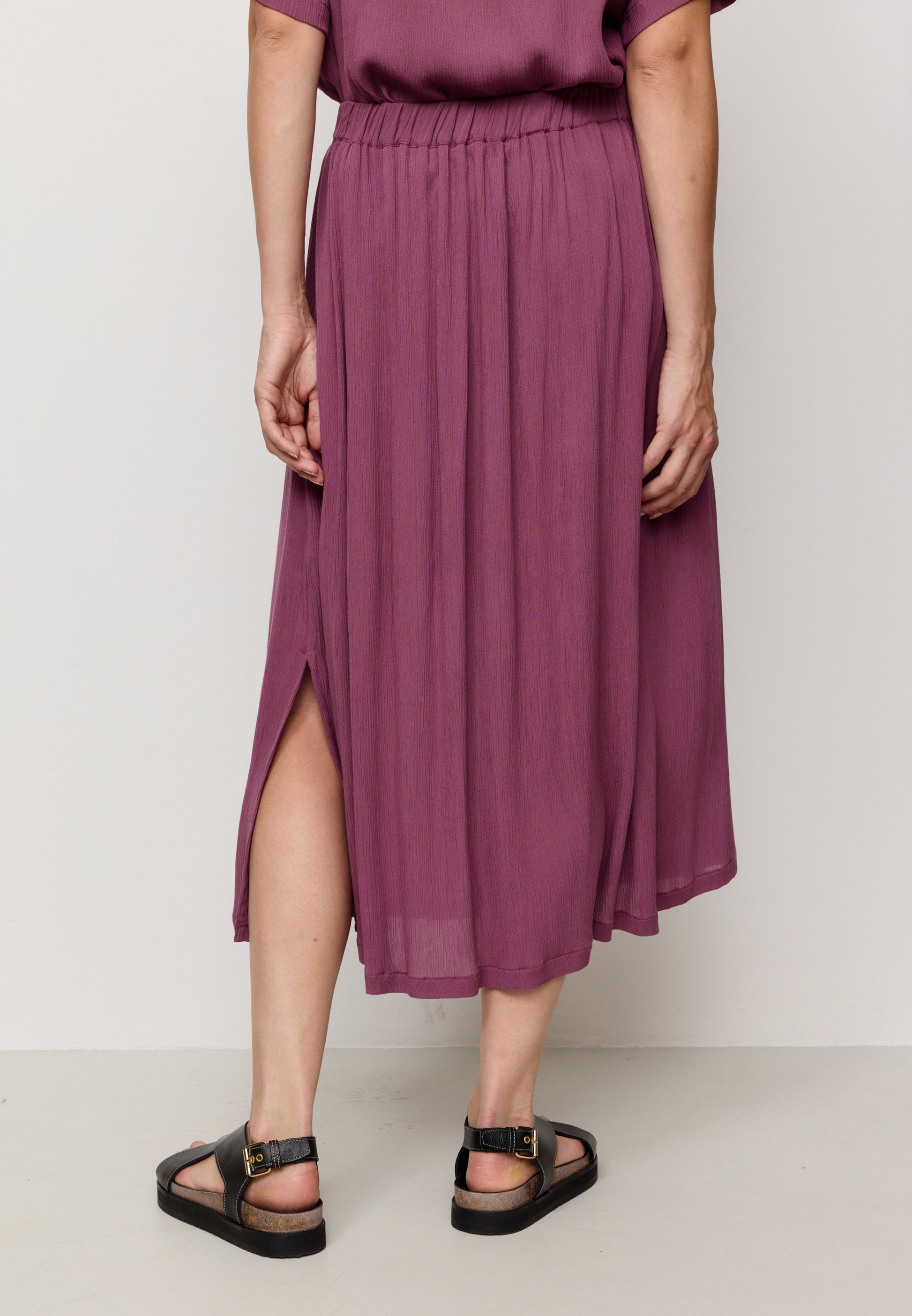 Person wearing a purple skirt with a plain background