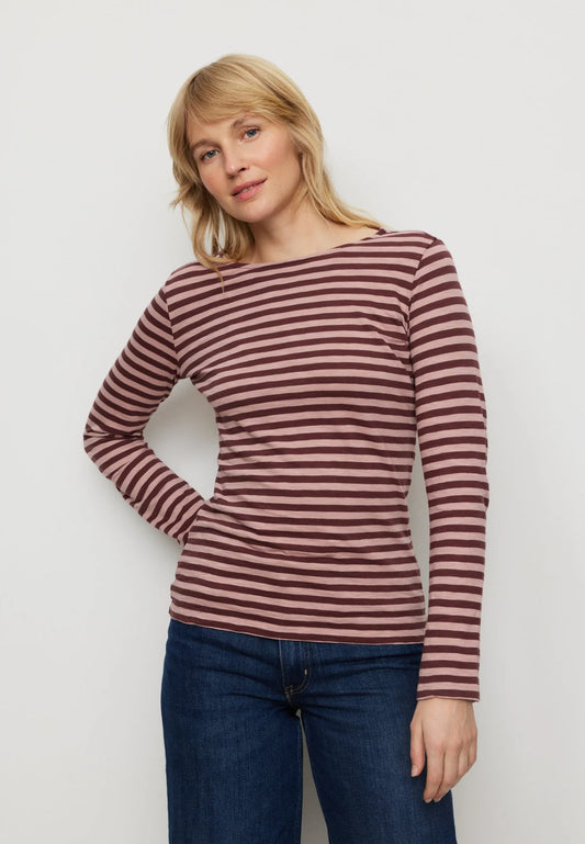 Woman wearing a striped long-sleeve shirt and jeans against a plain background