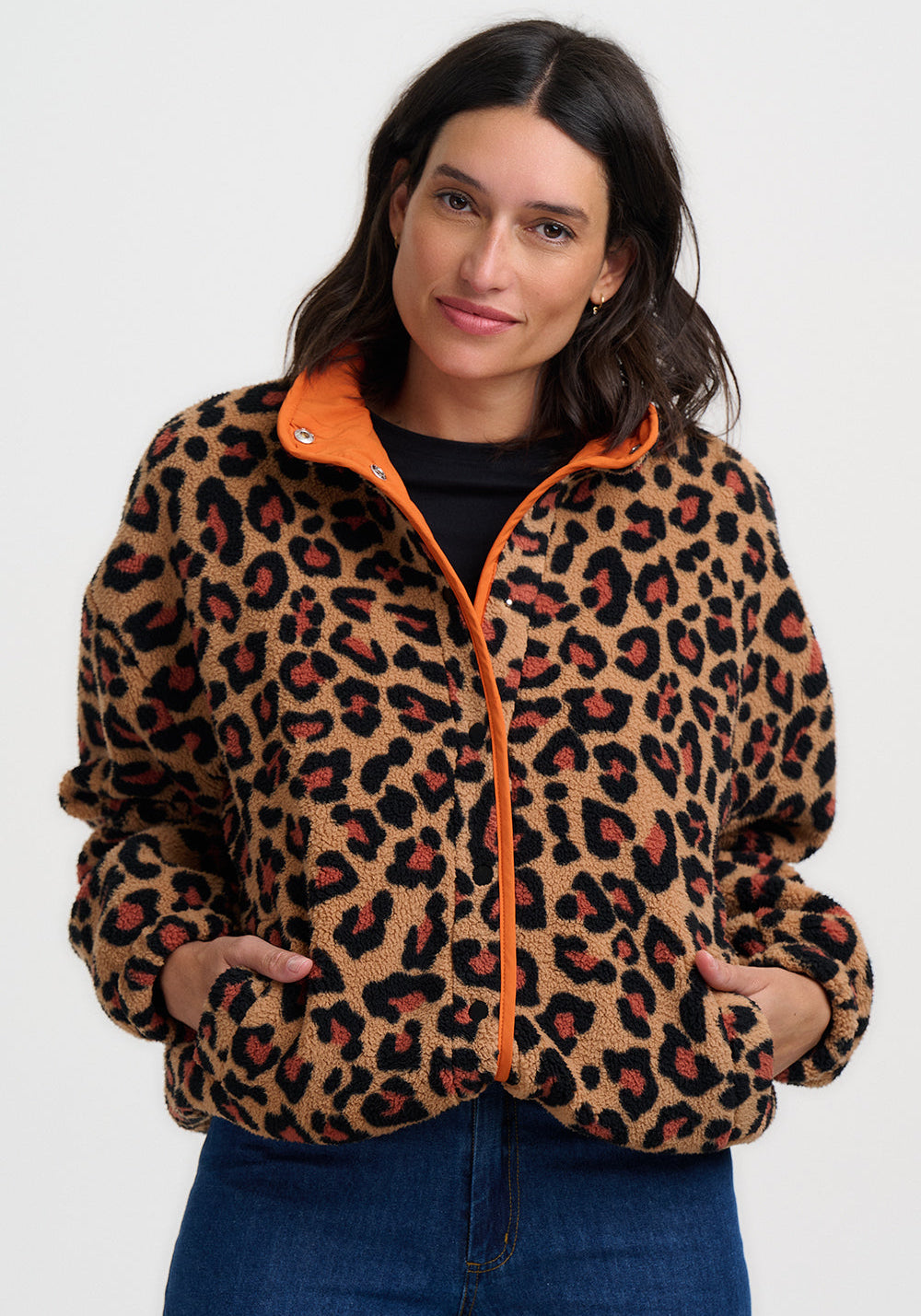 Woman wearing the Remi leopard print fleece jacket by Sugarhill Brighton with orange zipper on a white background