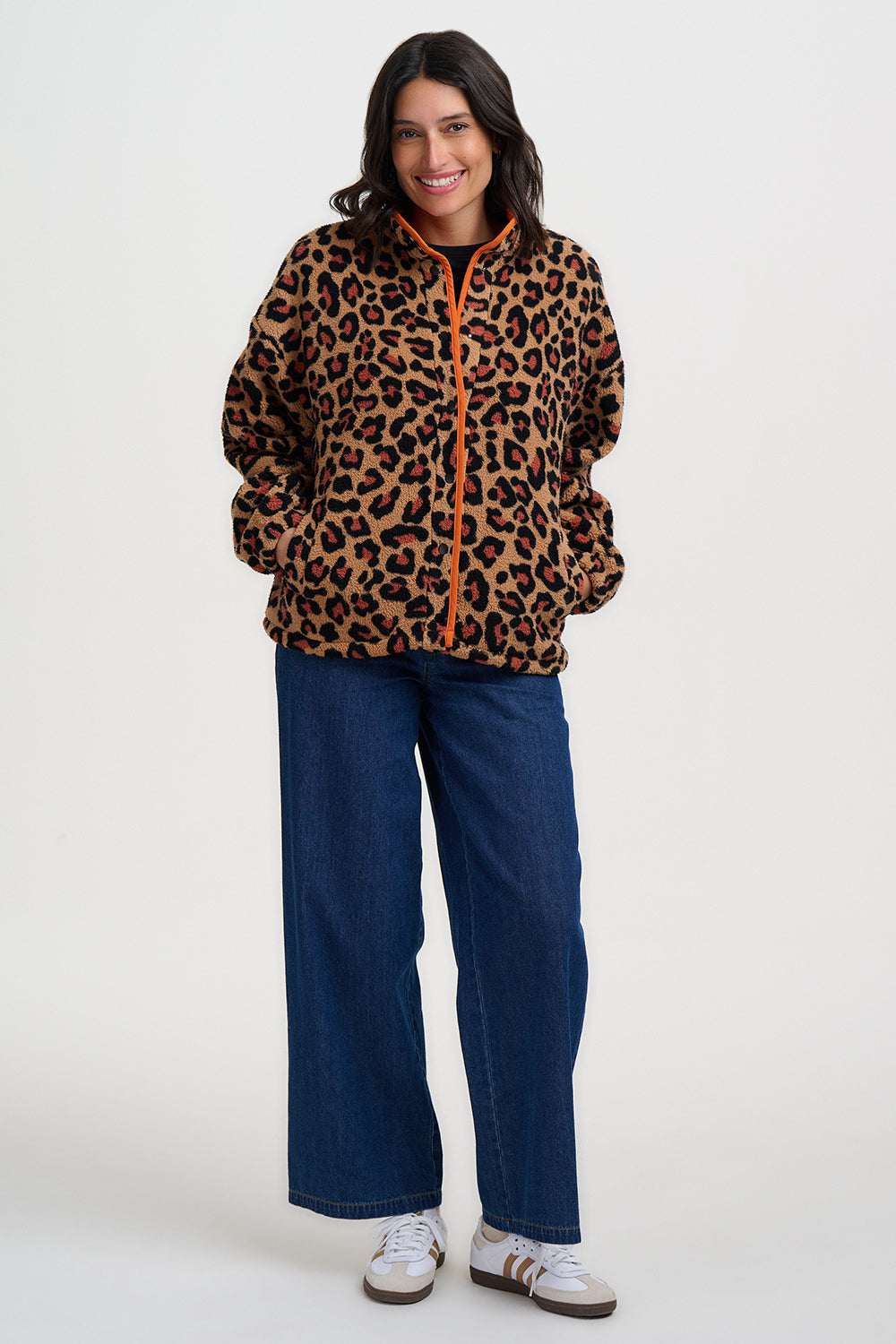 Woman wearing the Remi leopard print fleece jacket by Sugarhill Brighton and blue pants on a white background