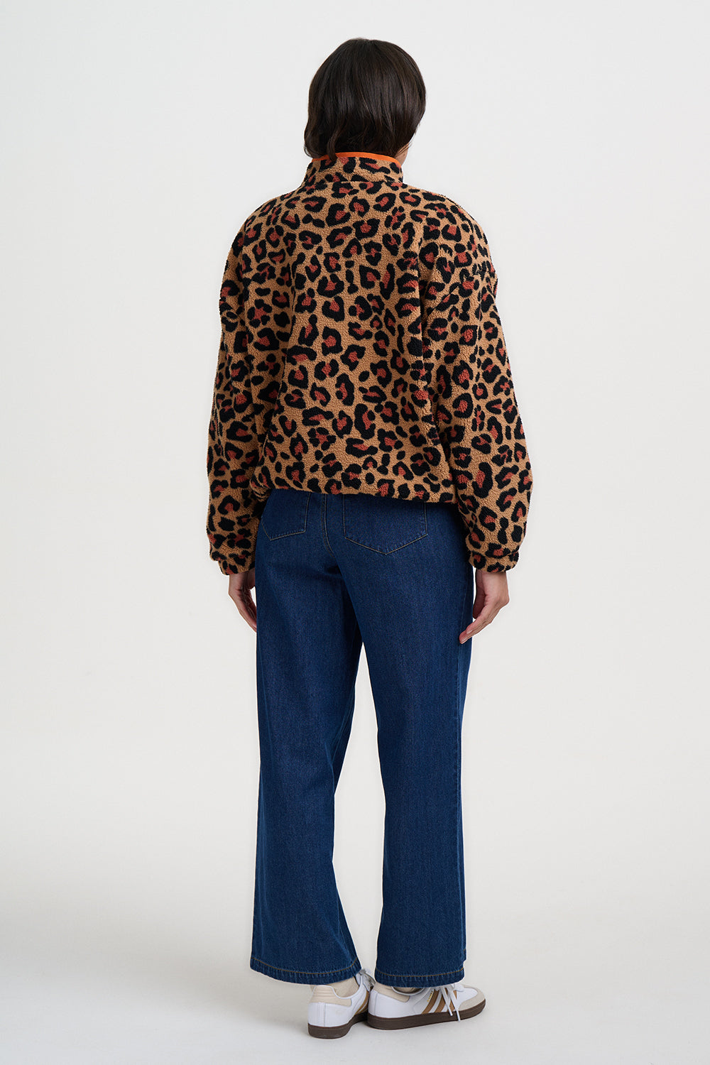 Person wearing a leopard print jacket and blue jeans on a white background