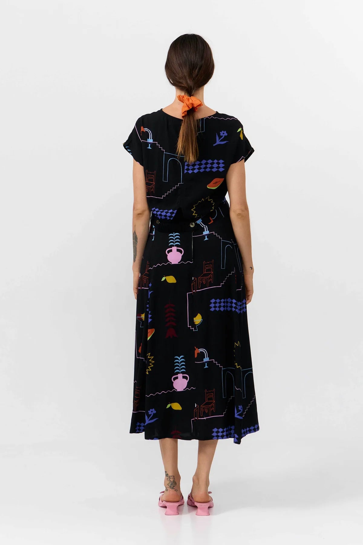 Woman wearing a black dress with colorful geometric patterns on a white background