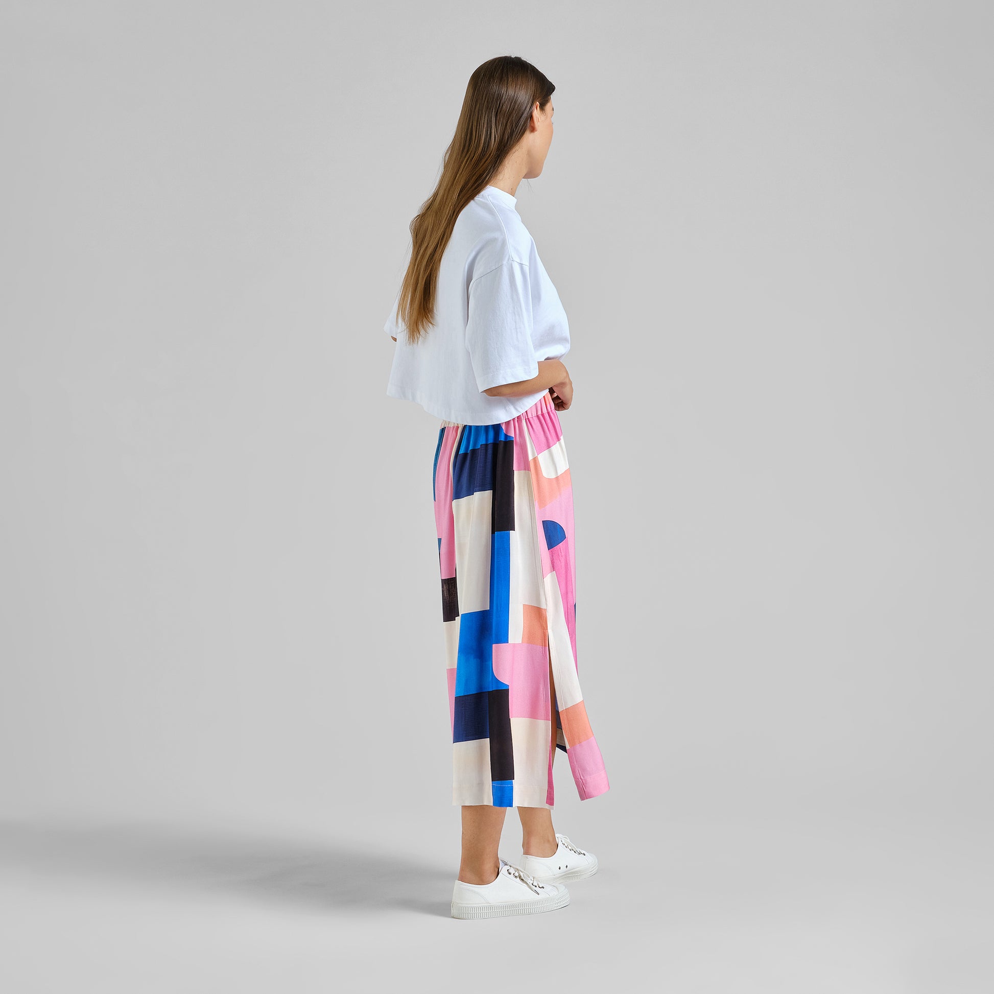 Woman wearing a colorful geometric-patterned skirt on a gray background