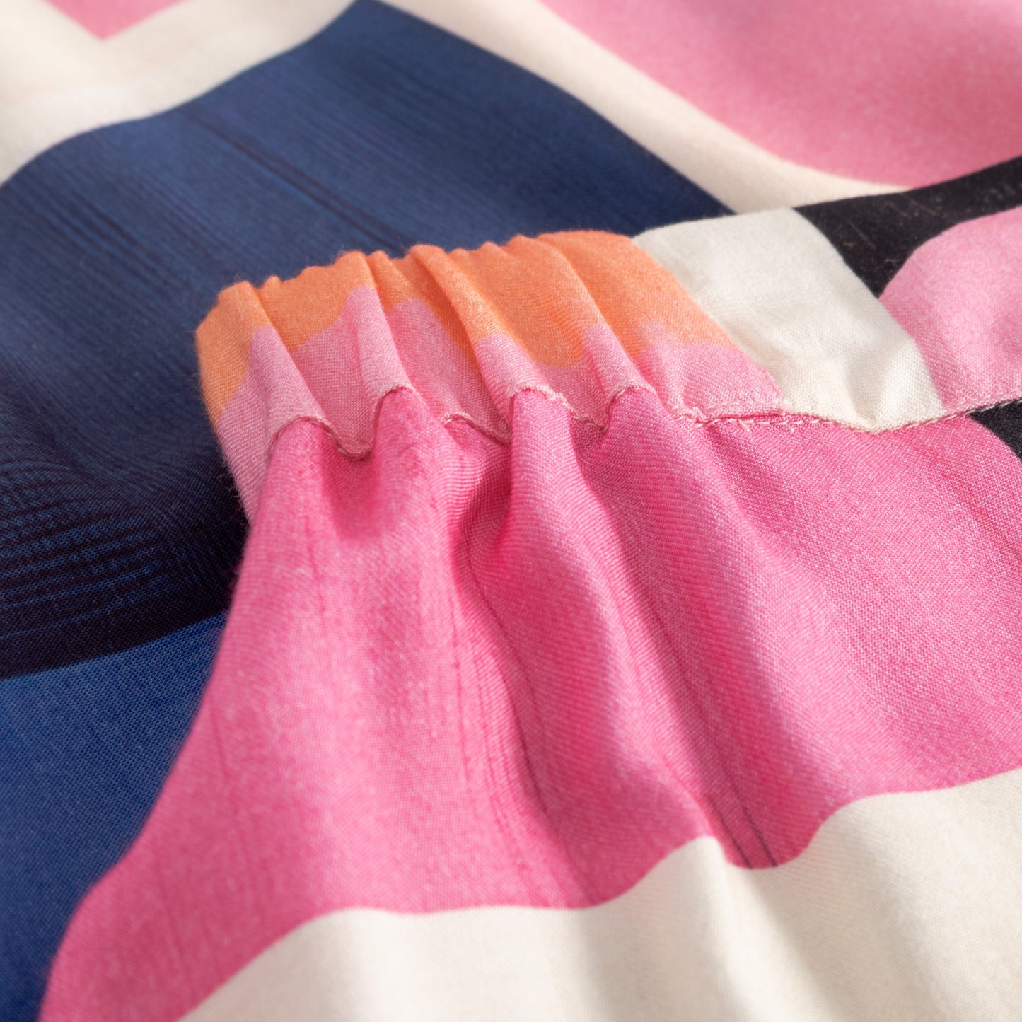 Close-up of a colorful fabric with pink, orange, and blue stripes.