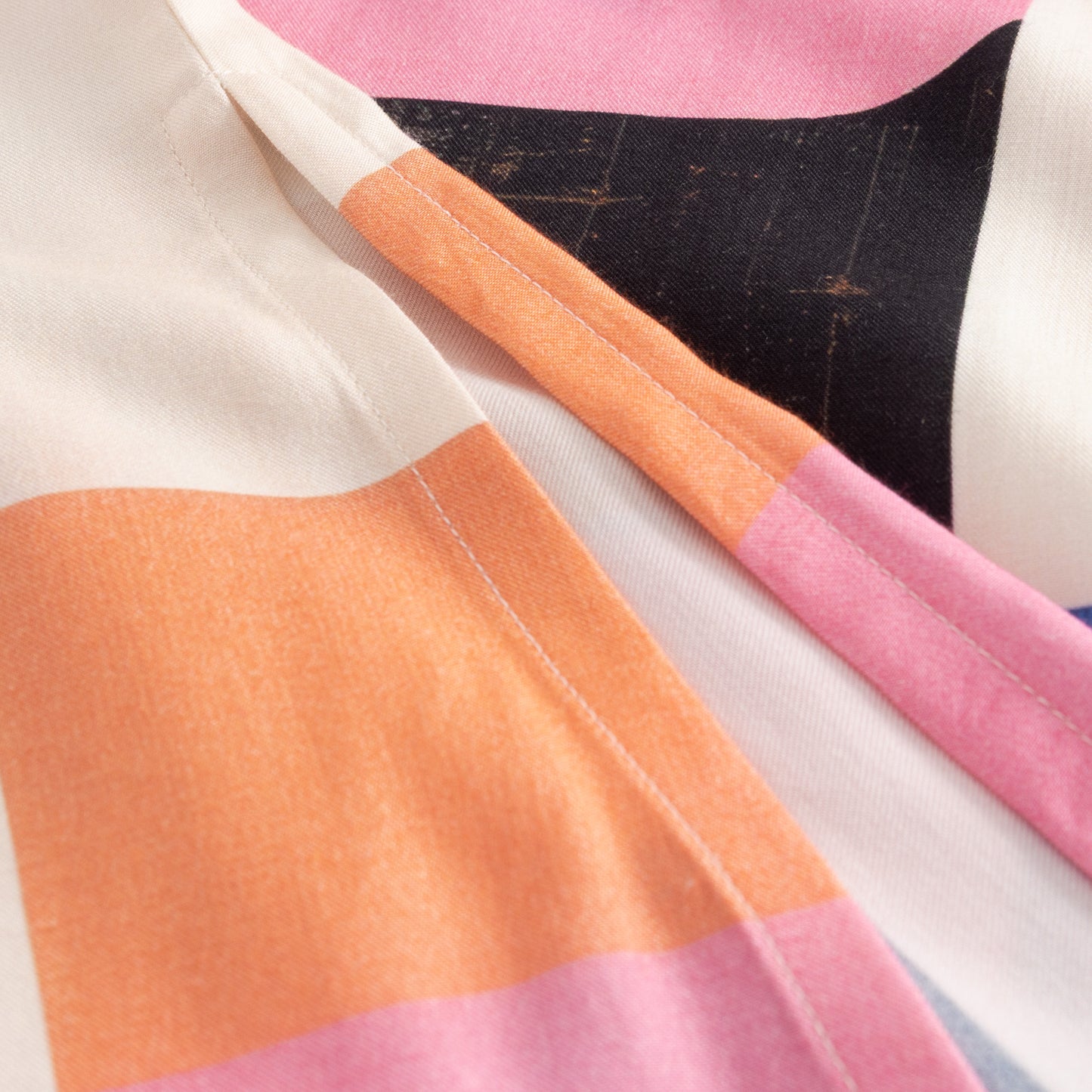 Close-up of a fabric with pink, orange, and black geometric pattern