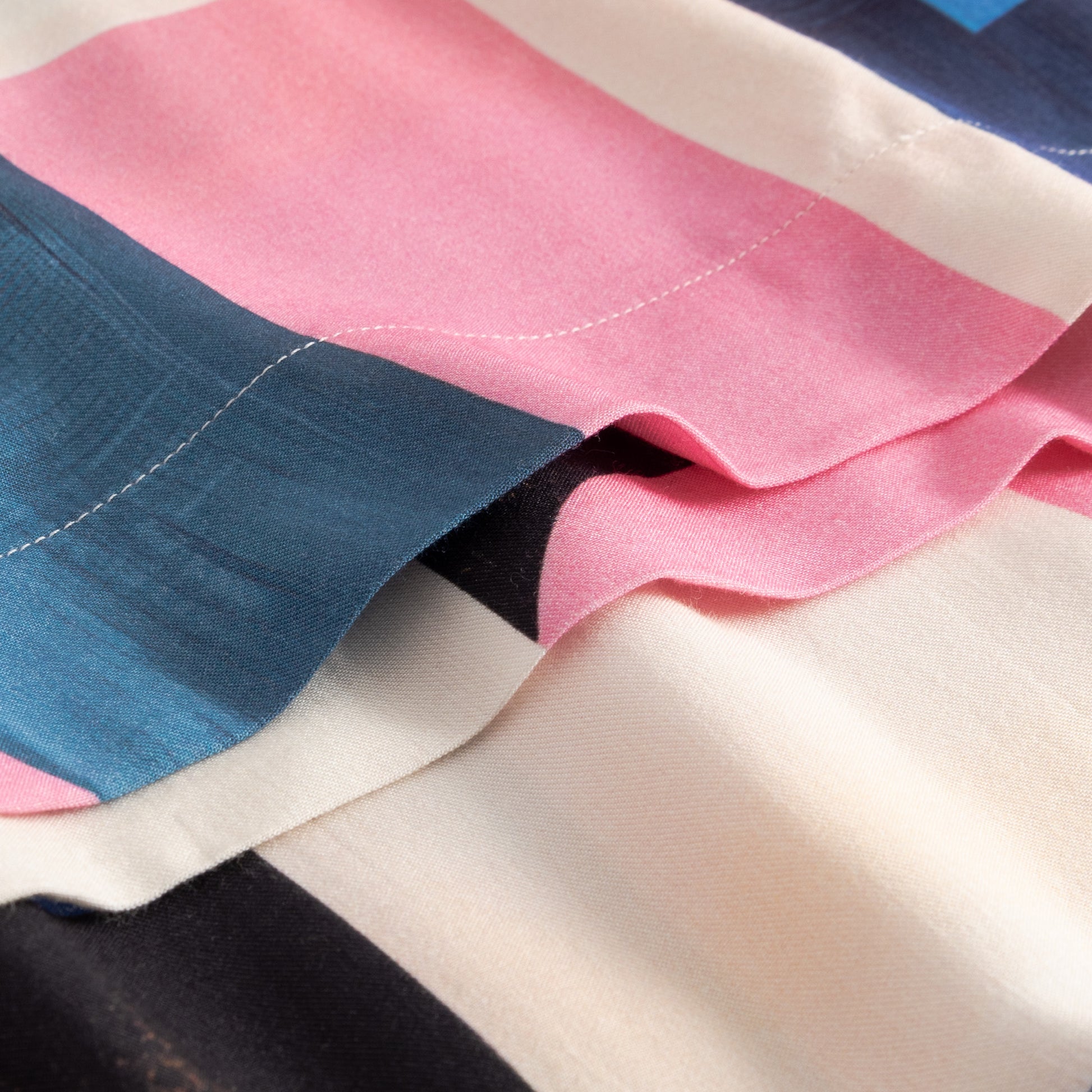 Close-up of fabric with pink, blue, beige, and black colors.