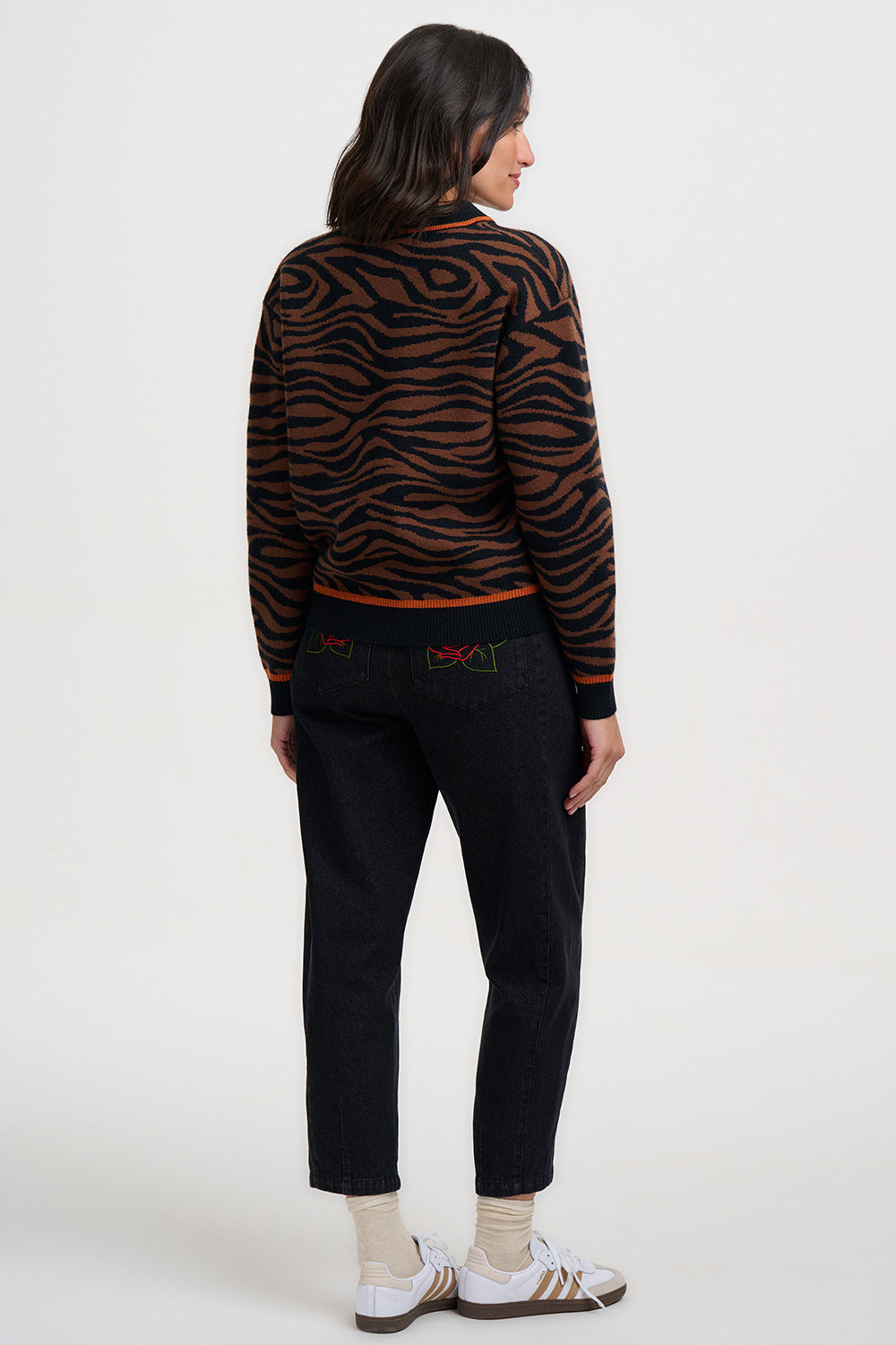 Woman wearing the tiger print Solana bomber jacket by Sugarhill Brighton and black pants on a white background
