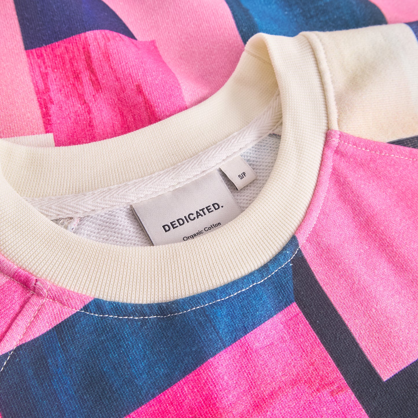 Close-up of a colorful sweater with a brand tag on a multicolored background
