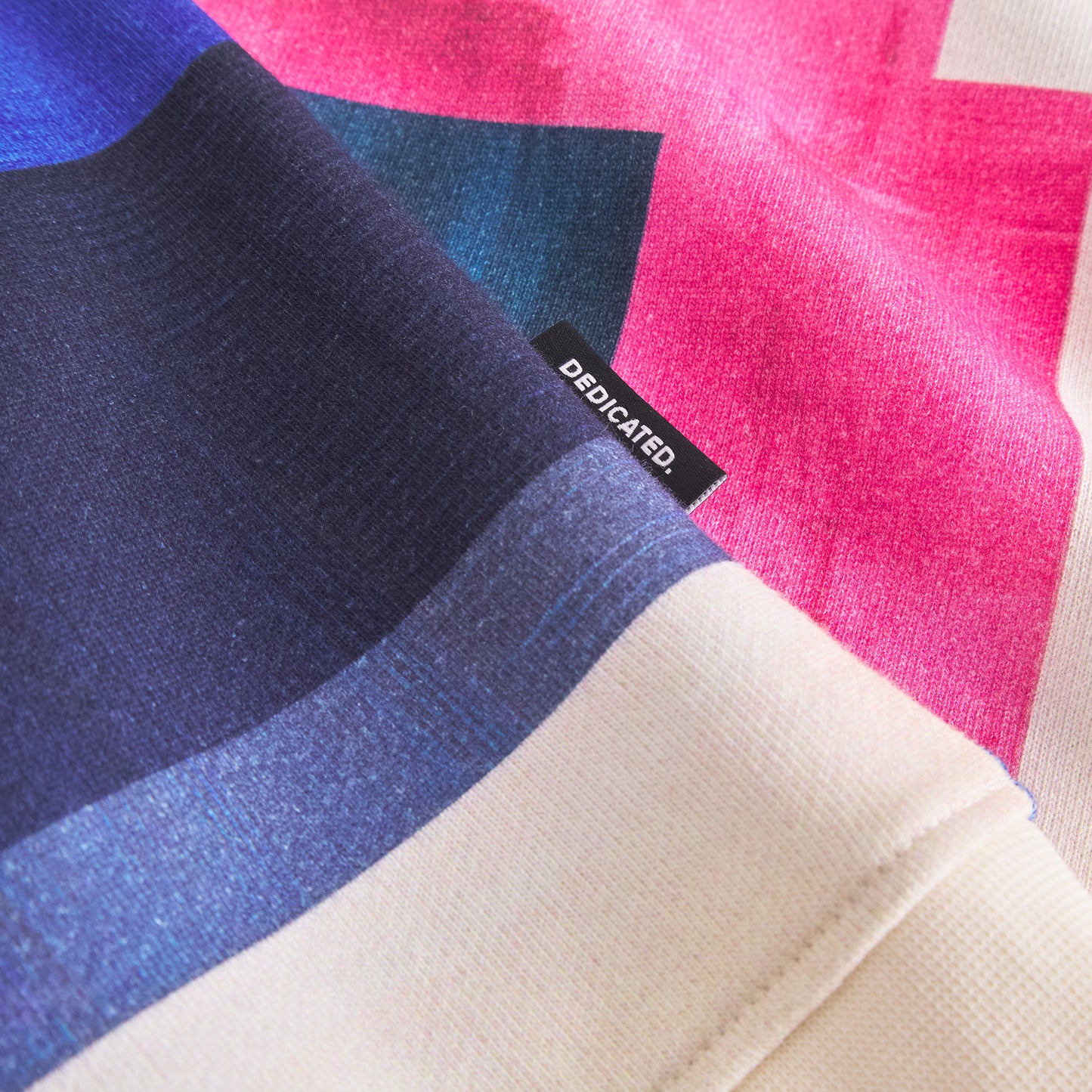 Colorful fabric with a 'Dedicated' label on a pink and blue background