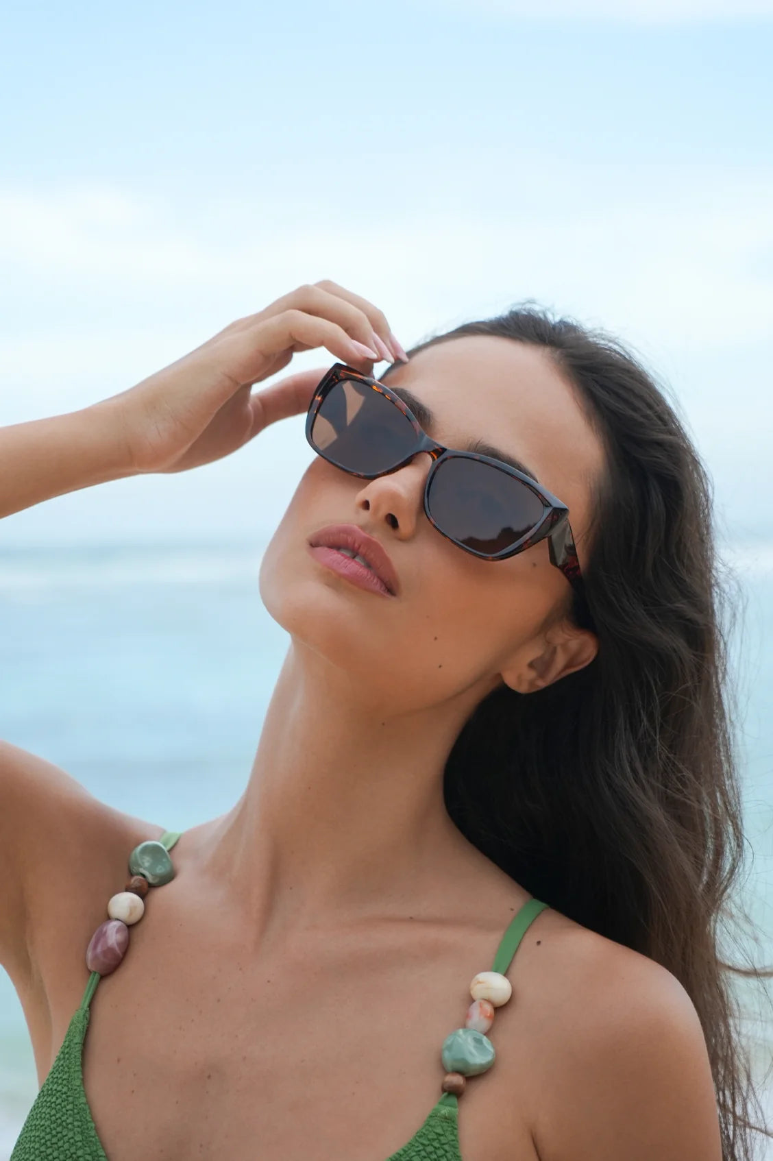 Woman wearing Sydney sunglasses from Estella Bartlett with a blurred beach background