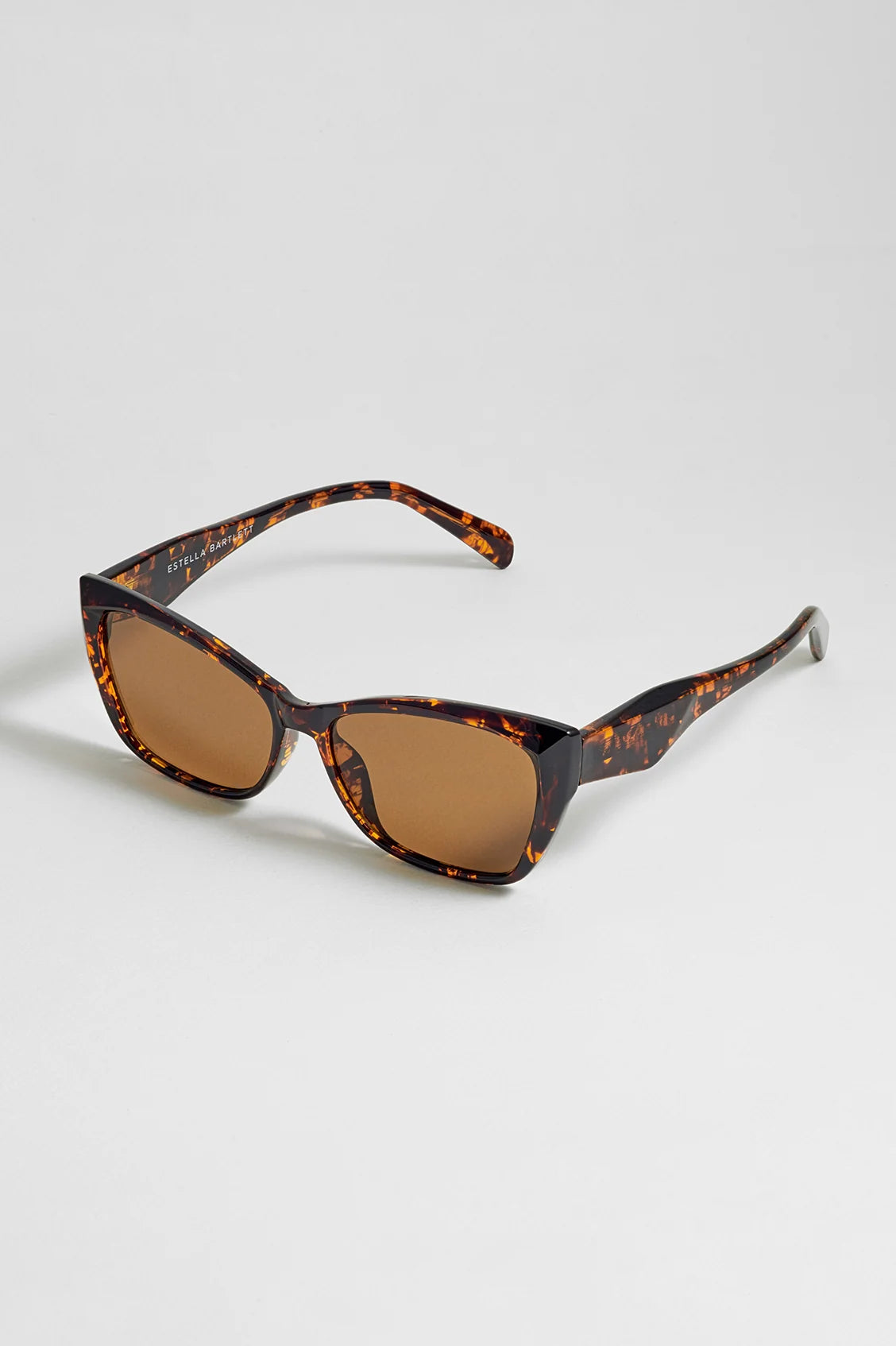 Estella Bartlett sunglasses with tortoiseshell frame and brown lenses on a light gray background