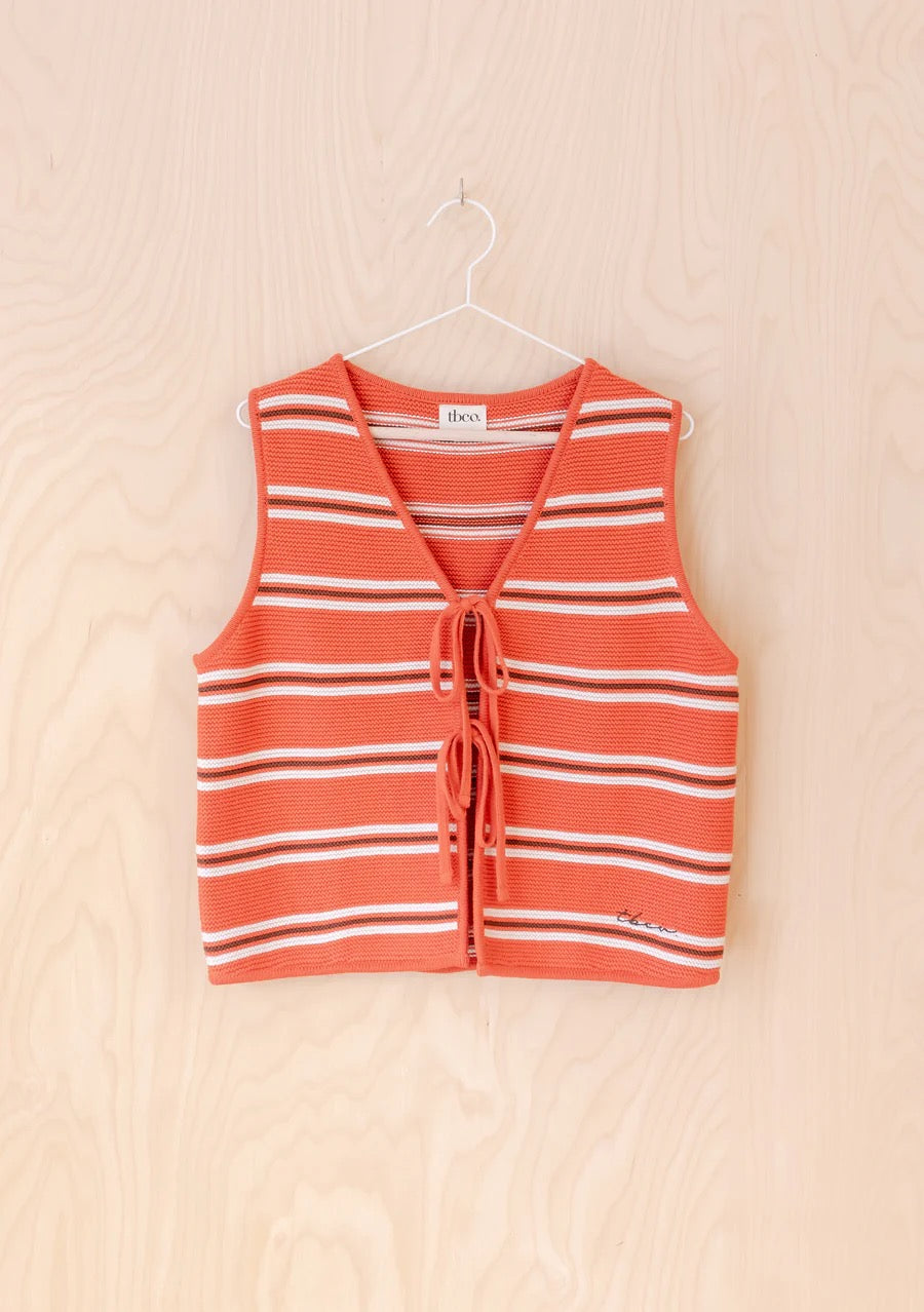 Knitted sleeveless vest from TBCo in a bold orange, with fine horizontal stripes in cream and dark brown. Made from 100% high-quality cotton. With two front ties for adjustable styling.