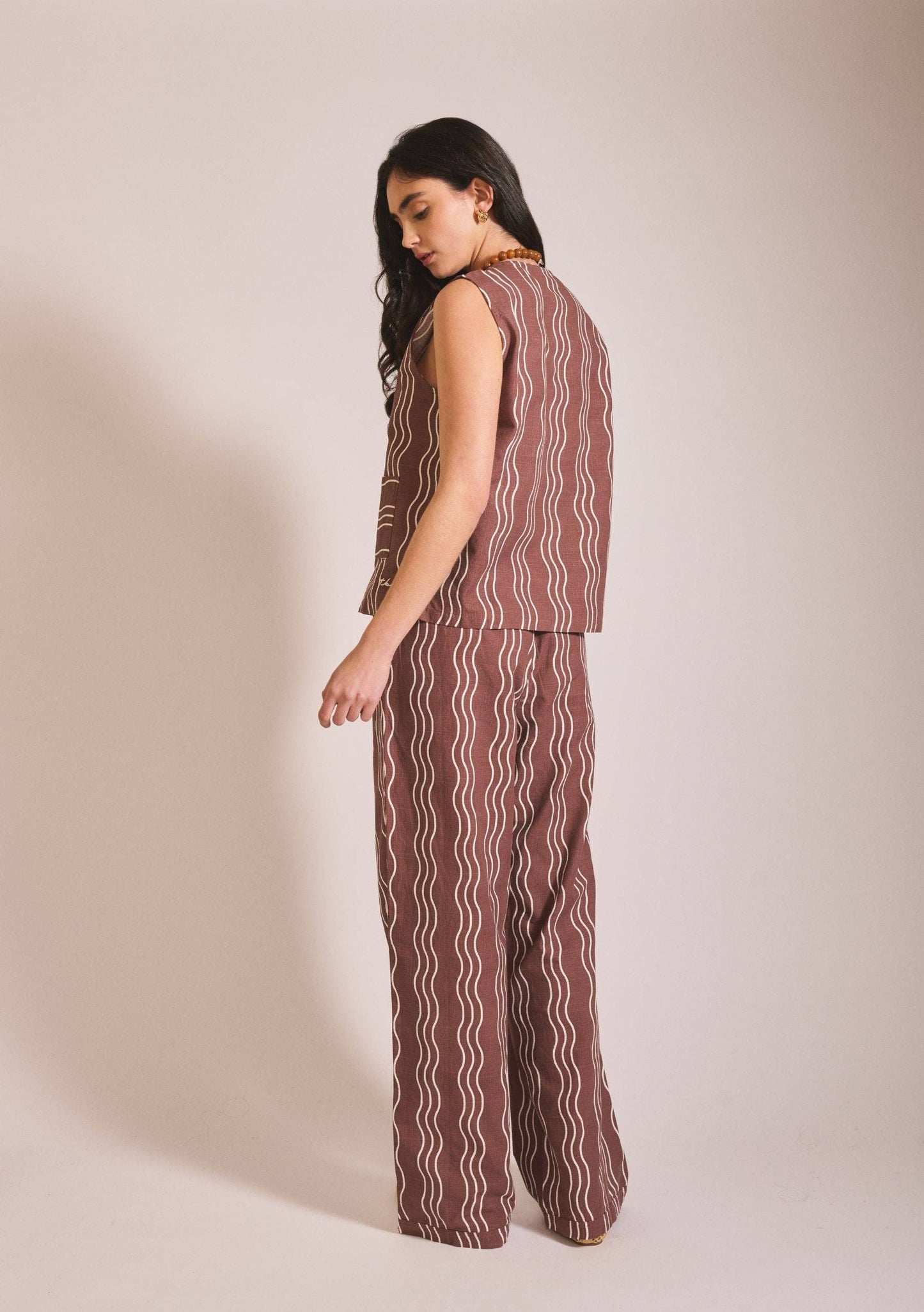Woman wearing a brown patterned outfit on a beige background