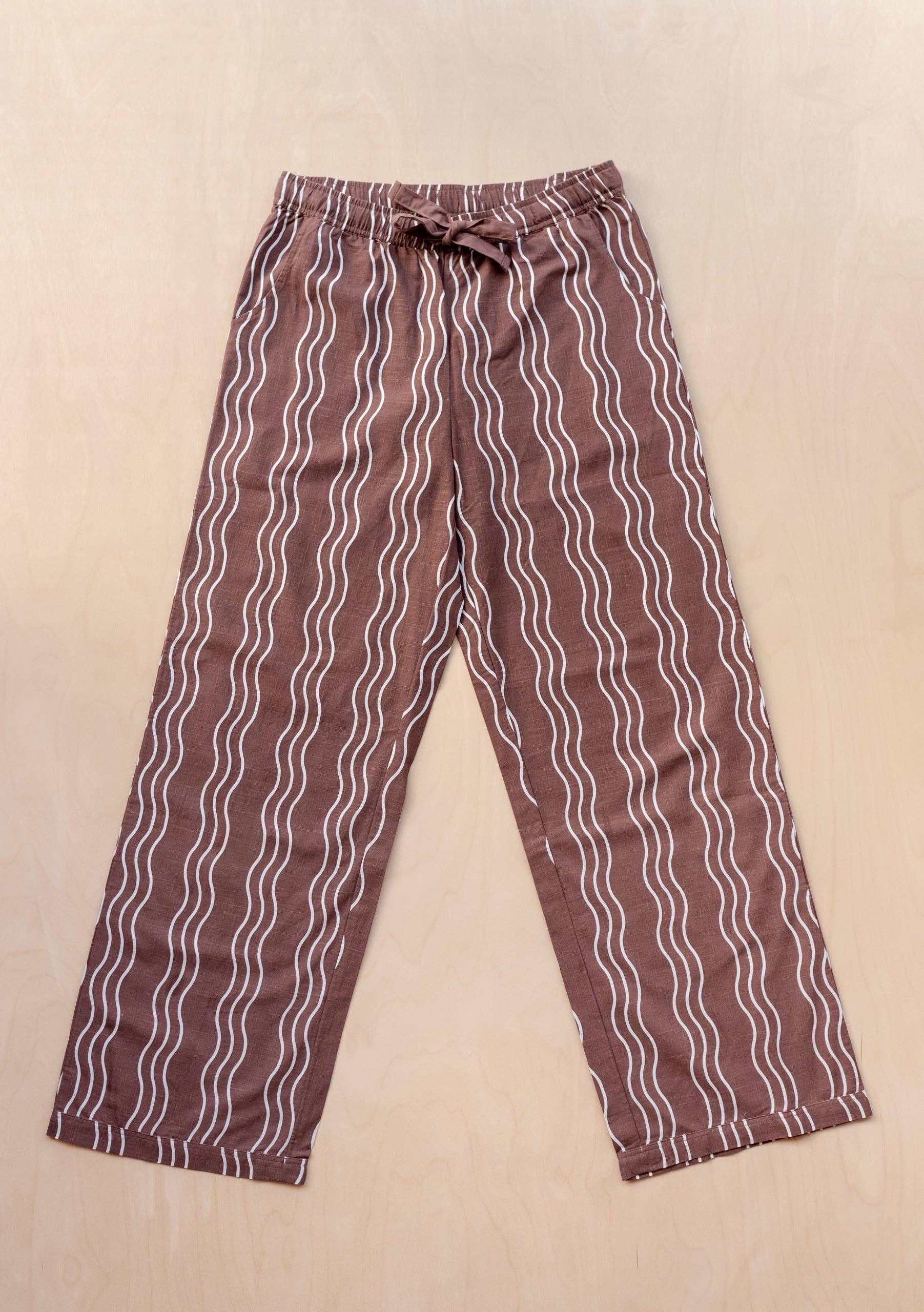 Pair of brown pants with white wavy lines on a beige background
